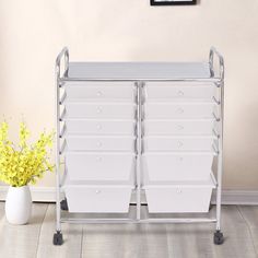 a white storage cart with two bins on wheels next to a yellow flower in a vase