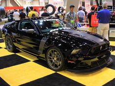 a black mustang car on display at an auto show