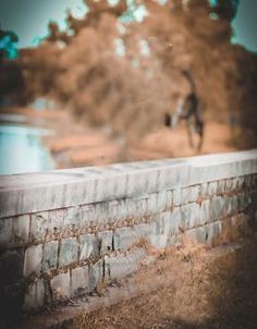 a blurry photo of a person walking on a sidewalk next to a brick wall