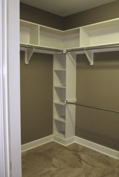 an empty walk in closet with white shelving and tan carpeted flooring is shown