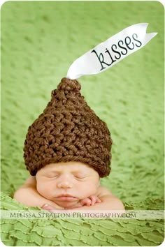 a baby wearing a brown crochet hat with a white arrow