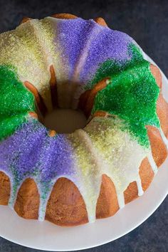 a bundt cake with purple, green and white icing on a white plate