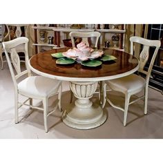 a dining room table with chairs and a flower centerpiece on top of the table