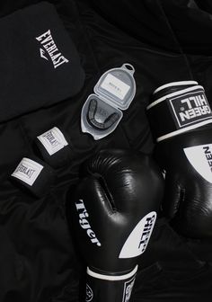 two black boxing gloves sitting next to each other on top of a blanket with tags