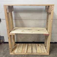 a wooden shelf sitting on top of a floor next to a white brick wall in a room