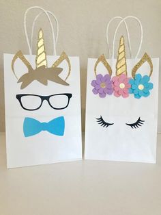 two paper bags with unicorns and flowers on them, one has a bow tie