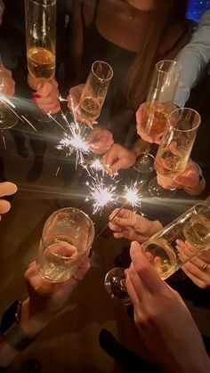 many people holding wine glasses with sparklers in them