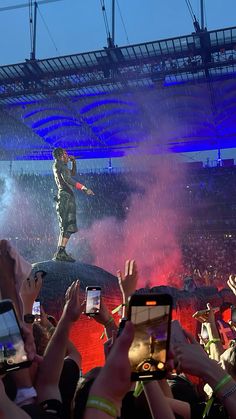 a man standing on top of a car in the middle of a crowd holding up their cell phones