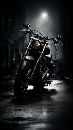 a black and white photo of a motorcycle parked in the rain with its headlights on