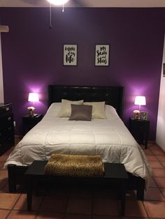 a bedroom with purple walls and white bedding, two lamps on either side of the bed