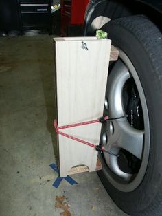 a wooden box tied to the side of a car tire with a red rope around it