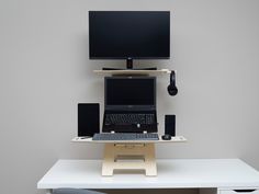 a laptop computer sitting on top of a white desk next to a monitor and speakers