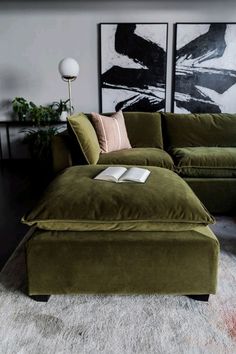 a large green couch sitting on top of a white rug next to a lamp and painting