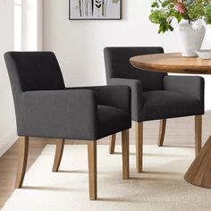 two grey chairs sitting at a round wooden table