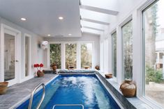 a large indoor swimming pool in the middle of a living room with glass doors and windows