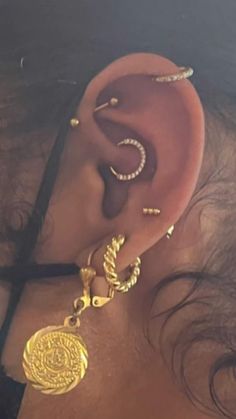 a woman with ear piercings and gold jewelry on her ears is looking at the camera