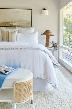 a bedroom with white bedding, pillows and a painting on the wall above it