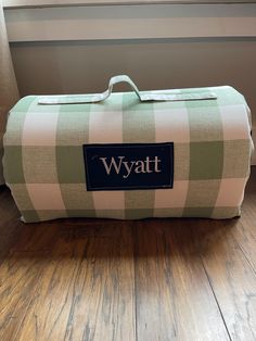 a green and white checkered duffel bag with the word wyatt on it