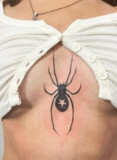 a spider tattoo on the back of a woman's rib - neck and chest