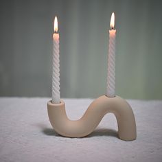 two white candles sitting on top of a table