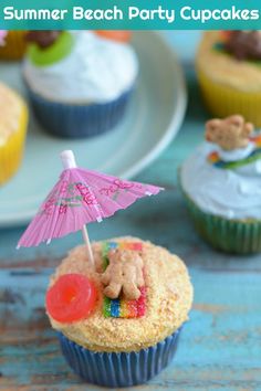 cupcakes with pink umbrella and teddy bear on top sitting next to other cupcakes