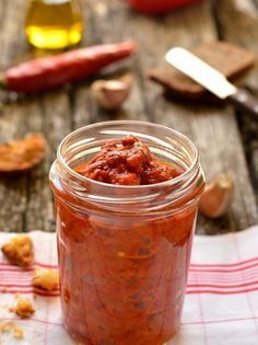 a jar filled with sauce sitting on top of a wooden table