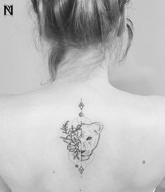 the back of a woman's neck with a bear and flowers tattoo on it