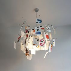 a chandelier hanging from the ceiling with paper cut out of different shapes and sizes