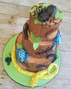 a cake made to look like a tree stump with bugs and leaves around it on a green plate