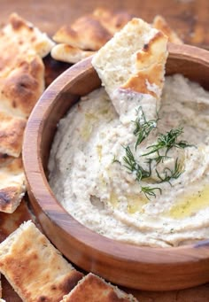 a wooden bowl filled with hummus and crackers