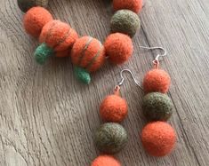 an orange necklace and earring set on a wooden table next to a ball ornament