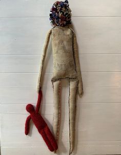 a stuffed doll is hanging on the wall next to a crocheted red teddy bear