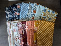 a bunch of different types of fabric sitting on top of a wooden table next to a computer