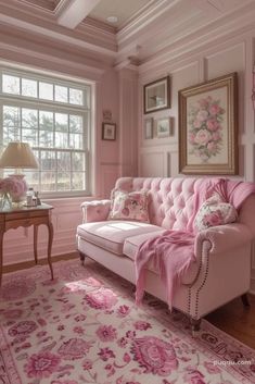 a living room with pink couches and paintings on the wall, rugs in front of large windows