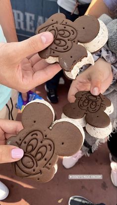 someone is holding up some cookies with mickey mouse cut out of them to be eaten