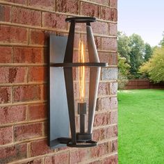 an outdoor wall light on the side of a brick building with grass in the background