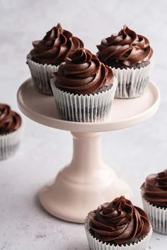 cupcakes with chocolate frosting on a cake stand