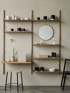 the shelves are filled with vases, plates and other items on them as well as a round mirror