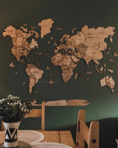 a wooden table topped with a vase filled with flowers and a world map on the wall