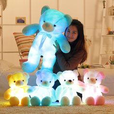 a woman holding a large teddy bear in front of several smaller stuffed bears on the floor