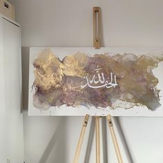 an easel with a painting on it in front of a white wall