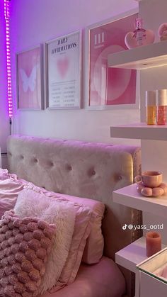 a bed with pink and white pillows on top of it next to a purple light