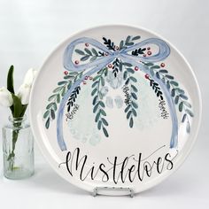 a plate with the words mistflowers painted on it next to a vase with flowers