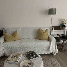 a living room with a white couch, coffee table and books on the end tables