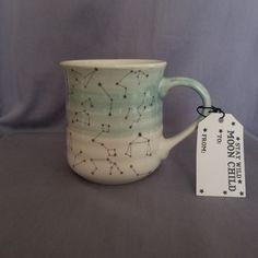 a ceramic mug with stars on it is next to a tag that says moon city