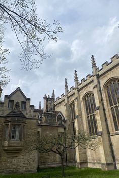 an old building with many windows and trees in the foreground on a cloudy day