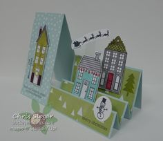 a card with some houses on it and santa's sleigh in the background