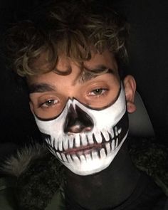 a young man with painted face and skull makeup looks at the camera while wearing a black t - shirt