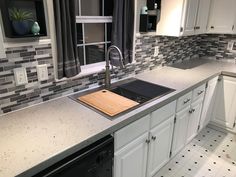 a kitchen with white cabinets and gray tile backsplash, black stove top oven and dishwasher