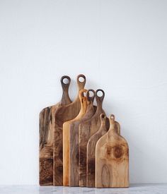 five wooden cutting boards are lined up on the wall